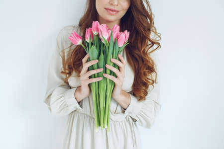 Beautiful woman with tulips. Spring bouquet in the hands of a young and happy girl. High quality photo.の写真素材