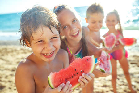 A group of children have fun playing at the sea. Children in bathing suits. Friends holding hands and running on the beach. High quality photo.の写真素材