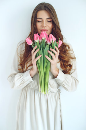 Beautiful woman with tulips. Spring bouquet in the hands of a young and happy girl. High quality photo.の写真素材