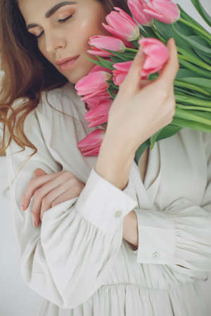 Beautiful woman with tulips. Spring bouquet in the hands of a young and happy girl. High quality photo.の写真素材