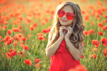 Beautiful child girl in a field of poppies, outdoor portrait. Child in a field with flowers. High quality photo.の写真素材