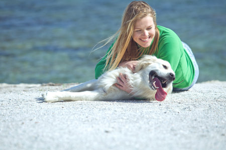 Cheerful pretty young woman hugs her dog on the beach. High quality photo.