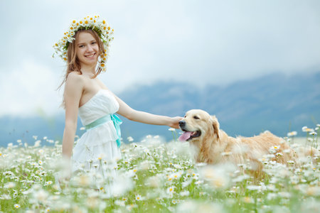 Lifestyle photo of a happy young girl with her pet dog Labrador Retriever in nature. High quality photo.の写真素材