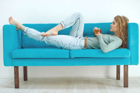 Young woman sitting at home and drinking tea, interior. High quality photo.の写真素材
