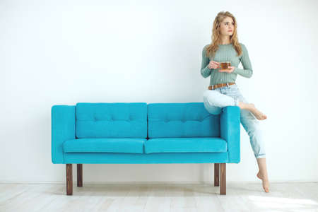 Young woman sitting at home and drinking tea, interior. High quality photo.の写真素材