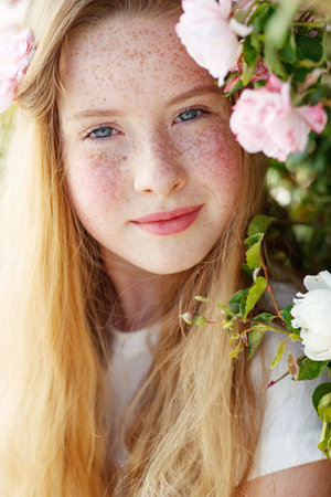 Girl on the nature of a rose. Beautiful red-haired girl near roses. High quality photo.の写真素材
