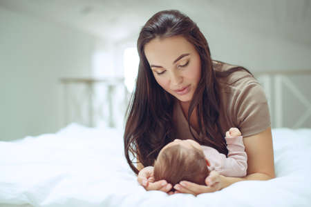 A young mother is holding her newborn baby. Mother of a nursing baby. Mother breastfeeding her baby. The family is at home. Portrait of a happy mother and child. High quality photo.の写真素材