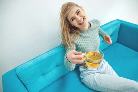 Young woman sitting at home and drinking tea, interior. High quality photo.の写真素材