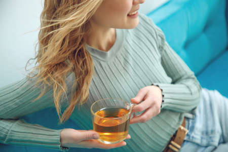 Young woman sitting at home and drinking tea, interior. High quality photo.の写真素材