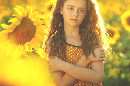Beauty joyful girl with sunflower enjoying nature and laughing at summer sunflower field. Sun glare, sun rays, shining sun. High quality photo.の写真素材