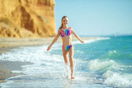 Child girl runs on the waves. Rest by the sea, fun outdoors. High quality photo.の写真素材