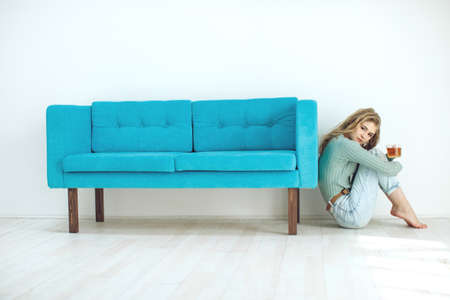 Young woman sitting at home and drinking tea, interior. High quality photo.の写真素材