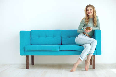 Young woman sitting at home and drinking tea, interior. High quality photo.の写真素材