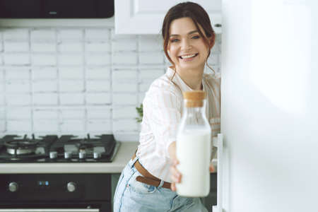 Young woman with milk at home in the kitchen. High quality photo.の写真素材