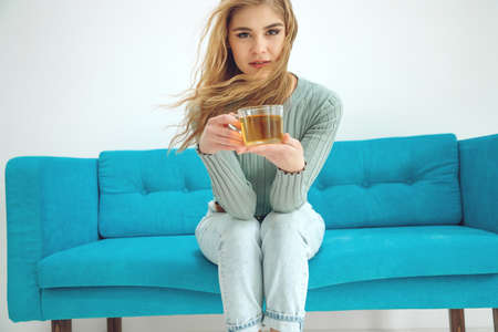 Young woman sitting at home and drinking tea, interior. High quality photo.の写真素材