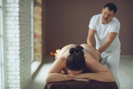 The masseur is giving massage to a fat woman. Spa massage for correction figure. Treatment massage for weight loss in spa salon. High quality photo.の写真素材