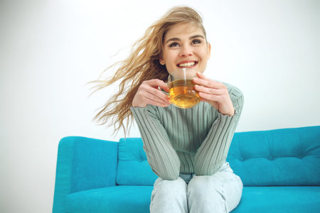 Young woman sitting at home and drinking tea, interior. High quality photo.の写真素材