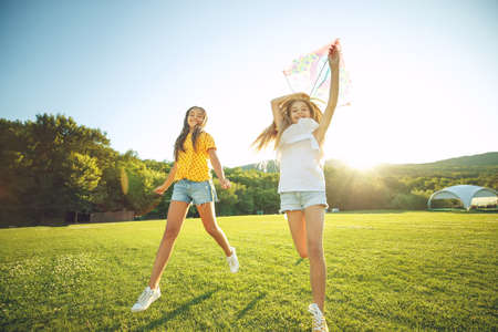 Children play in nature. A group of children runs on the grass in the park with a kite. High quality photo.の写真素材