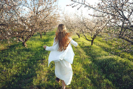 Girl in a blooming garden. A beautiful girl runs in a field with flowers. High quality photo.の写真素材