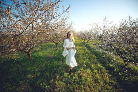 Girl in a blooming garden. A beautiful girl runs in a field with flowers. High quality photo.の写真素材