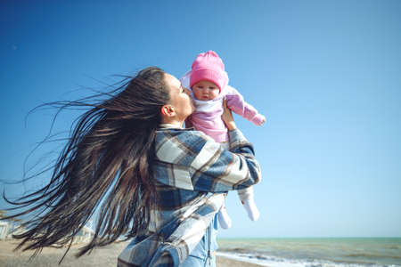 Woman with a child by the sea. Young mother with her baby by the sea in spring. High quality photoの写真素材