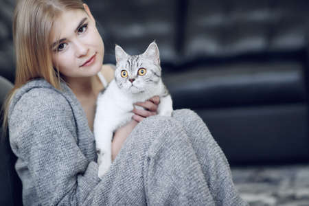 Woman at home with her lovely fluffy cat. Gray cute kitten with green eyes. Animals and lifestyle concepts. High quality photo.の写真素材