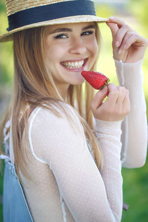 Shot of a young woman using fresh strawberries. Close-up of attractive woman with strawberry. High quality photo.の写真素材