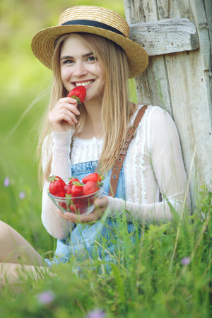 Shot of a young woman using fresh strawberries. Close-up of attractive woman with strawberry. High quality photo.の写真素材