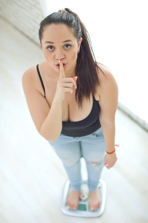 A fat woman weighs herself in and cannot wear good clothes. High quality photo.の写真素材