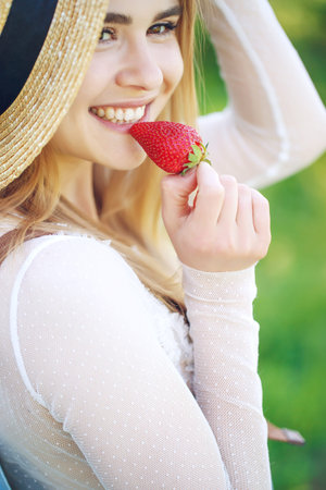 Shot of a young woman using fresh strawberries. Close-up of attractive woman with strawberry. High quality photo.の写真素材