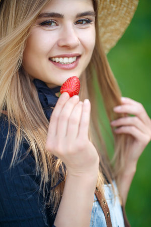 Shot of a young woman using fresh strawberries. Close-up of attractive woman with strawberry. High quality photo.の写真素材