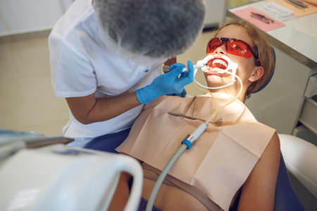 Teenage girl with braces visiting the orthodontist at the clinic. Installation of braces system. High quality photoの写真素材