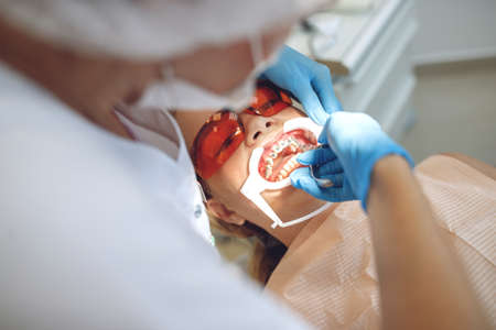 Teenage girl with braces visiting the orthodontist at the clinic. Installation of braces system. High quality photoの写真素材