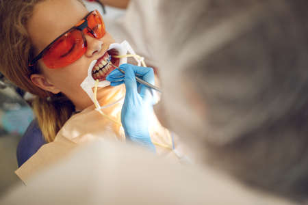 Teenage girl with braces visiting the orthodontist at the clinic. Installation of braces system. High quality photoの写真素材