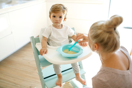 Mom feeds the baby. Young woman feeds her baby from a spoon at home. High quality photo.の写真素材