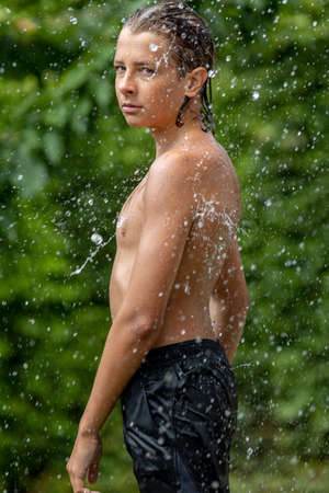 Guy teenager splashing water. Young handsome boy outdoors. High quality photoの写真素材