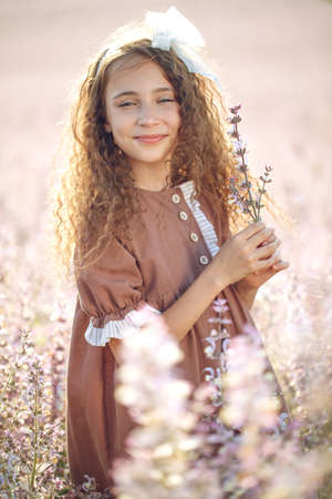 Girl in a field with flowers. Summer evening, little girl close-up in nature. High quality photoの写真素材