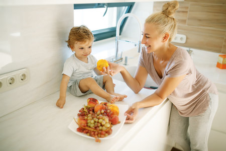 Mom feeds the baby. Young woman feeds her baby in the kitchen. High quality photoの写真素材