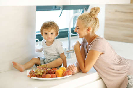 Mom feeds the baby. Young woman feeds her baby in the kitchen. High quality photoの写真素材