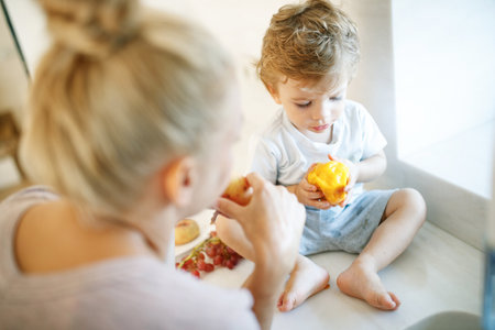 Mom feeds the baby. Young woman feeds her baby in the kitchen. High quality photoの写真素材