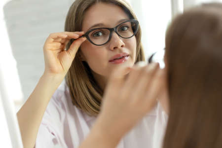 Woman with poor eyesight. A beautiful girl wears glasses to improve her vision. High quality photoの写真素材