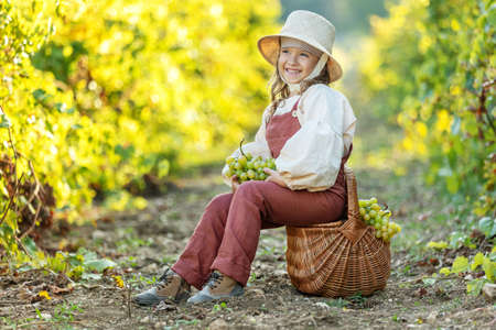 Beautiful little girl with grapes. Child with fruit. High quality photoの写真素材