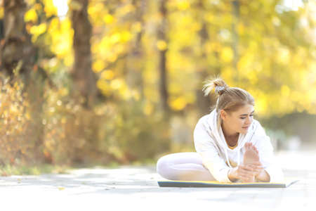 Woman practices yoga in the park. Girl in sports. High quality photoの写真素材