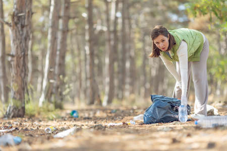 A woman removes rubbish in nature. Environmental pollution, environmental problem. High quality photoの写真素材