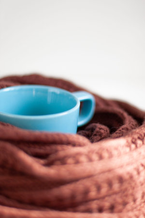 Autumn cold, illness. Blue mug, knitted scarf, thermometer