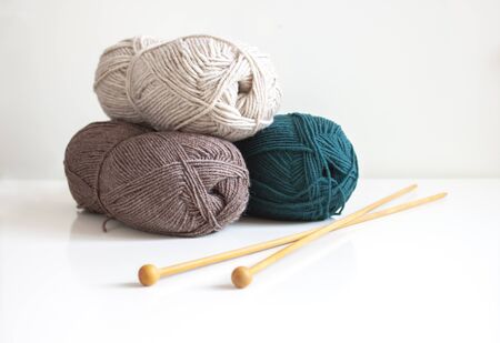 Knitting. Woolen yarn of green, coffee and milk color with wooden knitting needles for knitting on a white background. Copy spaceの写真素材