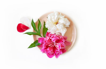 Pink and white peony flower on a plate and petals in the shape of a heart. Festive table decoration,...
