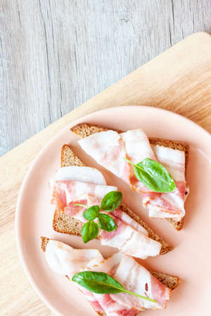 food, breakfast. A plate with sandwiches. Rye bread with bacon slice and basil leafの写真素材