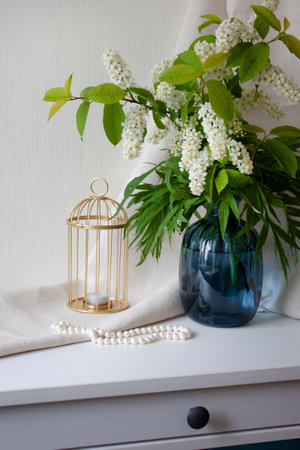 interior decor. Flowers in a blue glass vase, a golden candlestick and pearl beads. selective focusの写真素材