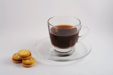 A glass of black coffee with biscuit on white backgroundの素材